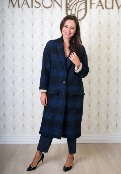 Woman wearing the Pam Coat sewing pattern from Maison Fauve on The Fold Line. A coat pattern made in wool, tweed or fake fur fabrics, featuring a wide cut, low armhole, V-neck, shawl collar, large patch pockets, maxi length, fully lined, turned back cuffs and front button closure.