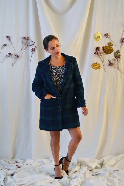 Woman wearing the Ray Coat sewing pattern from Maison Fauve on The Fold Line. A coat pattern made in wool, Jacquard or velvet fabrics, featuring a lowered button fastening, piped pockets with flaps, folded sleeve with buttoned strap, collar extending into elongated lapels and attached back belt.