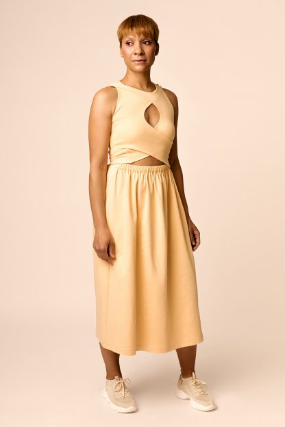 Woman wearing the Sisko Interlace Dress and Top sewing pattern from Named on The Fold Line. A dress pattern made in medium weight knit fabrics, featuring an elastic waist, layered and interlaced wrap bodice with ties and keyhole detail at the front, midi-length skirt, sleeveless, scoop neck, maternity and breastfeeding friendly.