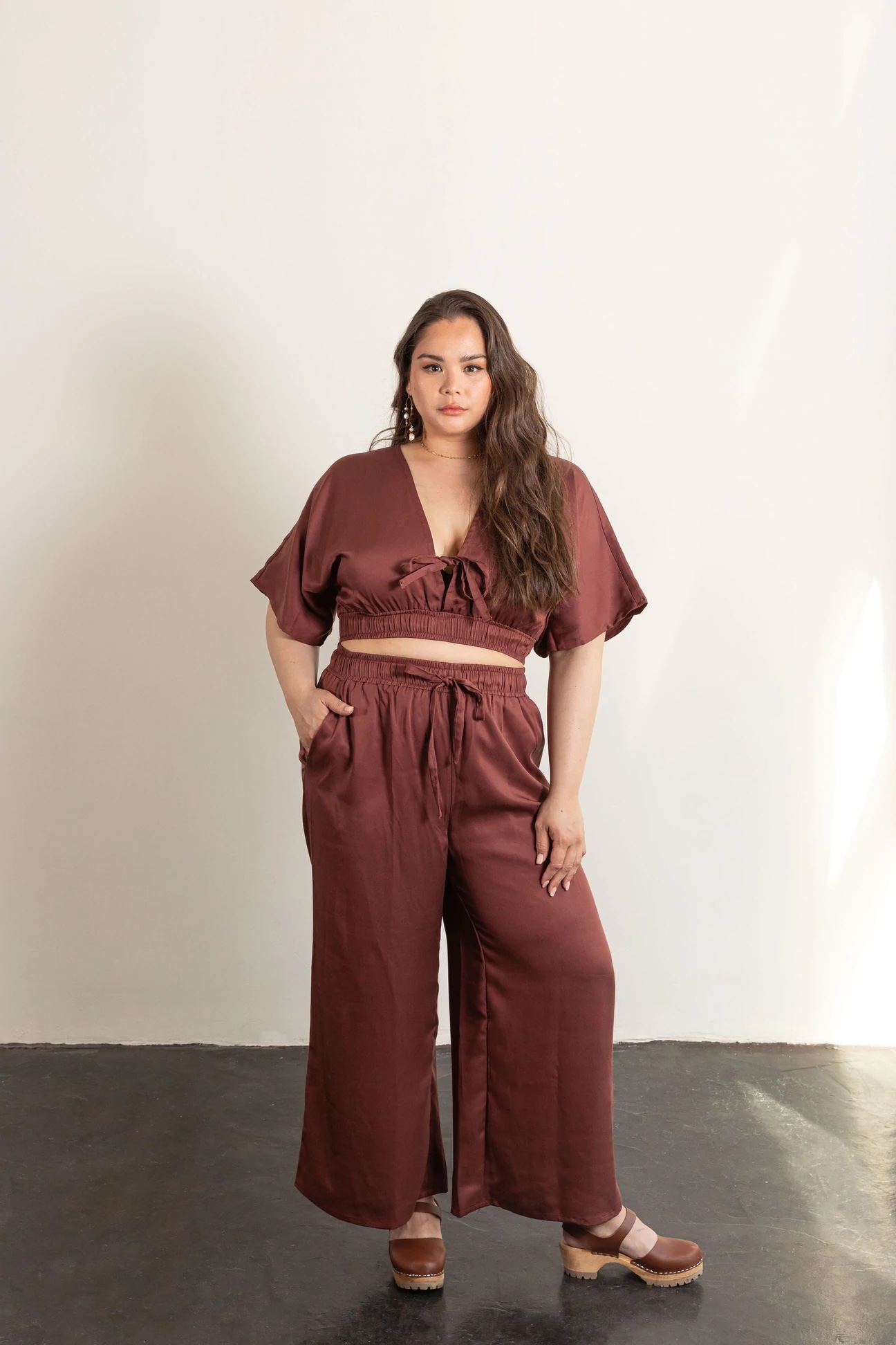 Woman wearing the Saguaro Set sewing pattern from Friday Pattern Company on The Fold Line. A trouser and top pattern made in linen, rayon, tencel, silk or cottons fabrics, featuring trousers with wide legs, relaxed fit, pockets, elasticated waist with drawstring. The top has a plunging V neckline with tie closure, elbow length sleeves, cropped length and relaxed fit.