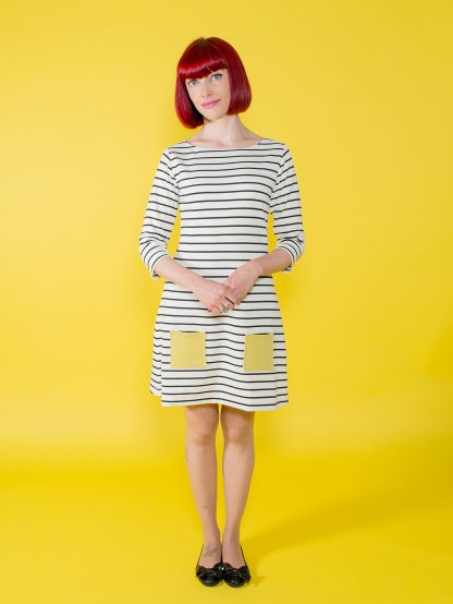 Woman wearing the Coco Dress sewing pattern from Tilly and the Buttons on The Fold Line. A dress pattern made in knit fabrics, featuring a boat neck, ¾ length sleeves, front patch pockets, and above knee length hem.