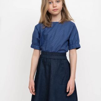 Child wearing the Children's Elastic Waist Skirt Mini sewing pattern from The Assembly Line on The Fold Line. A skirt pattern made in light to mid-weight fabrics, featuring an elasticated waistband, relaxed fit, large patch pockets and knee length finish.