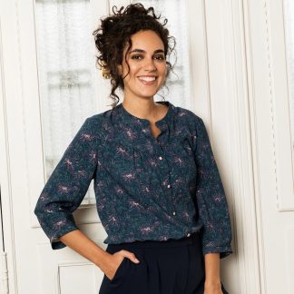 Woman wearing the Frida Blouse sewing pattern from Atelier Jupe on The Fold Line. A blouse pattern made in cotton, viscose, linen or tencel fabrics, featuring a front yoke with gathers, back yoke with inverted pleat, button placket, three-quarter sleeves and round collar.
