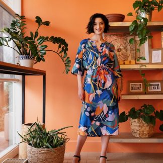 Woman wearing the Lynn Caftan Dress sewing pattern from Atelier Jupe on The Fold Line. A dress pattern made in viscose, cotton, linen or jersey fabrics, featuring a relaxed fit, large popover placket, wide sleeves, waist casing with ribbon and midi length hem.