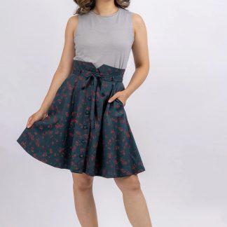 Woman wearing the Natalie Skirt sewing pattern from Forget-me-not Patterns on The Fold Line. A skirt pattern made in cotton chambray, cotton voile, linen, denim or stable viscose/rayon fabrics, featuring a button-front, gored style lines, slash pockets, raised waistband with diagonal seams, A-line silhouette and above knee length hem.