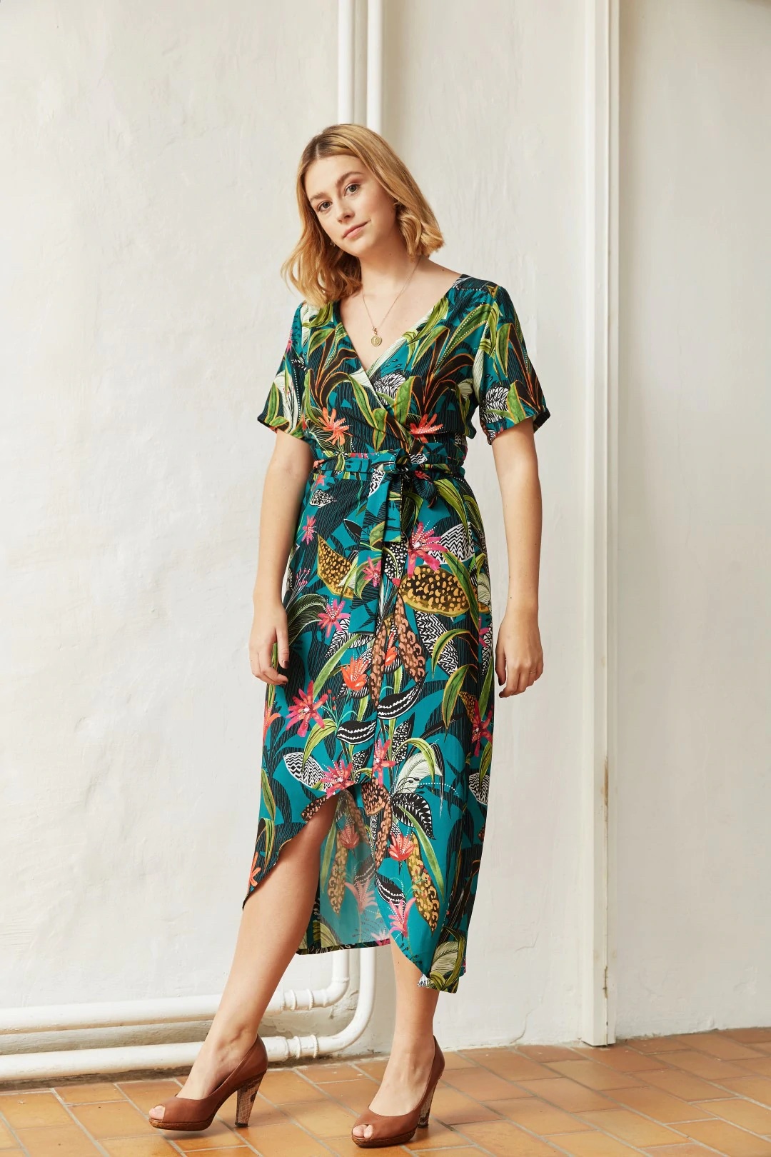 Woman wearing the Savannah Wrap Dress sewing pattern from Atelier Jupe on The Fold Line. A wrap dress pattern made in viscose or tencel fabrics, featuring short sleeves, fitted bodice with fine pleats and asymmetric skirt with high-low hem.