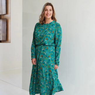 Woman wearing the Sienna Winter Dress sewing pattern from Atelier Jupe on The Fold Line. A dress pattern made in viscose or tencel fabrics, featuring a midi-length, loose-fitting bodice, long sleeves, 1/3 circle skirt, elasticated waist and round neckline.