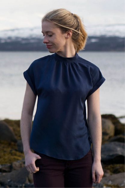 Woman wearing the Tulip Top sewing pattern from Wardrobe by Me on The Fold Line. A top pattern made in cotton, silk or viscose fabrics, featuring short cuffed dolman sleeves, a curved hem, and neckline gathered to the collar.