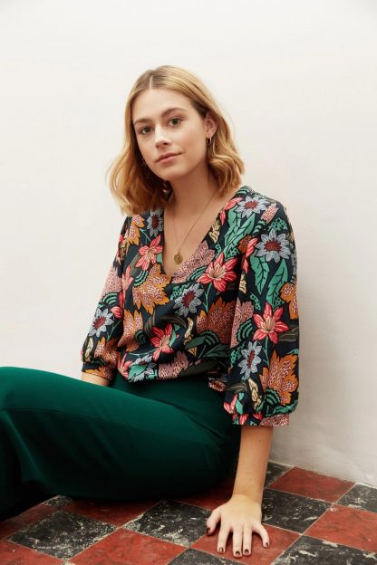 Woman wearing the Zoey Blouse sewing pattern from Atelier Jupe on The Fold Line. A blouse pattern made in viscose or tencel fabrics, featuring a loose-fit, V-neck, bust darts and voluminous three-quarter sleeves gathered at the cuff.