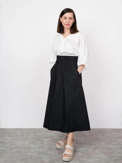 Woman wearing the Elastic Waist Maxi Skirt sewing pattern from The Assembly Line on The Fold Line. A skirt pattern made in cotton poplin, denim, wool, faux leather or cotton twill fabrics, featuring an elasticated waistband, relaxed fit, large patch pockets with decorative stitching and midi length.