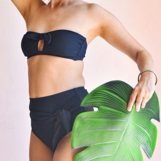 Woman wearing the Cuba Libre Bikini sewing pattern from Fitiyoo on The Fold Line. A bikini pattern made in two-way stretch fabrics, featuring a bandeau bra with central cut-out and high-waisted briefs with front, self-fabric tied knot.