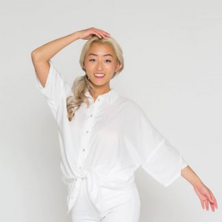 Woman wearing the Finja Blouse sewing pattern from Bara Studio on The Fold Line. A blouse pattern made in viscose, cotton linen or tencel fabrics, featuring an oversized fit, classic shirt collar, button placket, high-low curved hem line and dropped sleeves in ¾ length.