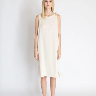 Woman wearing the Freja Knot Dress sewing pattern from Bara Studio on The Fold Line. A sleeveless dress pattern made in cotton, linen or tencel fabrics, featuring a loose-fit, side slits, knot on the left shoulder, in-seam pockets, scoop neckline and knee length hem