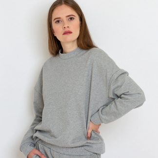 Woman wearing the Hanna Sweater sewing pattern from Bara Studio on The Fold Line. A sweater pattern made in medium-weight stretch fabrics such as sweat or French terry fabrics, featuring an oversized silhouette, dropped shoulders, ribbed neckline, hem and sleeve cuffs.