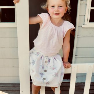 Child wearing the Mānuka Skirt sewing pattern from Below the Kōwhai on The Fold Line. A skirt pattern made in linen, cotton or chambray fabrics featuring a knee-length, elastic back waistband and faux button band.
