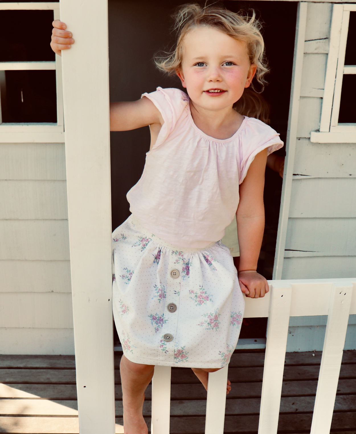 Child wearing the Mānuka Skirt sewing pattern from Below the Kōwhai on The Fold Line. A skirt pattern made in linen, cotton or chambray fabrics featuring a knee-length, elastic back waistband and faux button band.