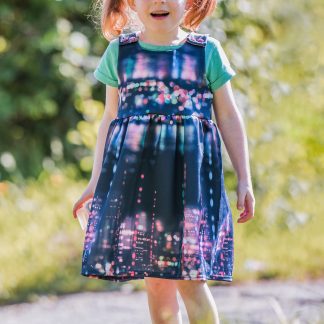 Child wearing the Over More Dress sewing pattern from Waves & Wild on The Fold Line. A pinafore pattern made in cotton/Lycra french terry, sweatshirt fleece or cotton/Lycra jersey fabrics, featuring a gathered skirt, in-seam pockets and tie shoulders.