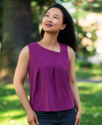Woman wearing the Sentosa Tank sewing pattern from Itch to Stitch on The Fold Line. A tank top pattern made in jersey, double-brushed poly or viscose French terry fabrics, featuring an asymmetrical neckline with pleats, relaxed fit and high hip length.