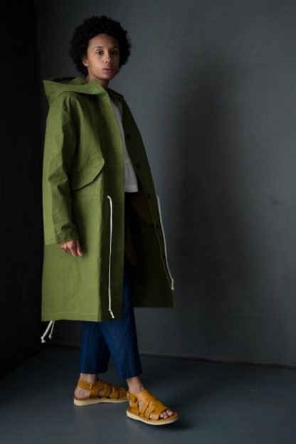 Woman wearing the TN31 Parka sewing pattern from Merchant & Mills on The Fold Line. A coat pattern made in oilskin, tweed, woollens, cotton drill, cotton canvas or waterproof cottons and linens fabrics, featuring an addition of a hood, attached or detachable, lined with self or fabric.