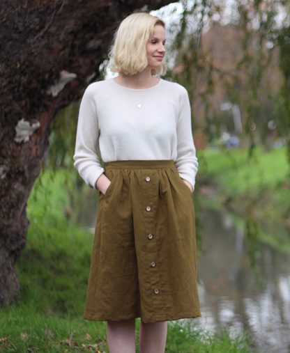 Woman wearing the Mānuka Skirt sewing pattern from Below the Kōwhai on The Fold Line. A skirt pattern made in linen, cotton, sateen, corduroy or chambray fabrics featuring a below knee finish, elastic back waistband, faux button band and pockets.