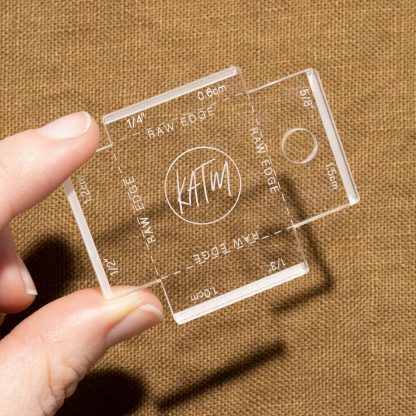 Photo showing the Label Gauge from Kylie & The Machine on The Fold Line. A clear acrylic gauge to help position your labels, includes the four most common seam allowances.
