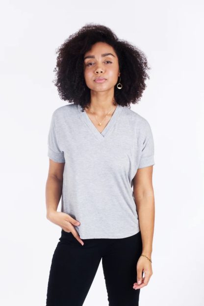 Woman wearing the Tabor V-neck Top sewing pattern from Sew House Seven on The Fold Line. Tee pattern made in lightweight fluid knit fabrics such as rayon, bamboo or cotton, linen, and hemp jerseys, wool jersey or novelty sweater knits fabrics, featuring a loose fit, drop shoulders, semi-deep V-neck with lapped neckband, cropped straight hem and short sleeves.