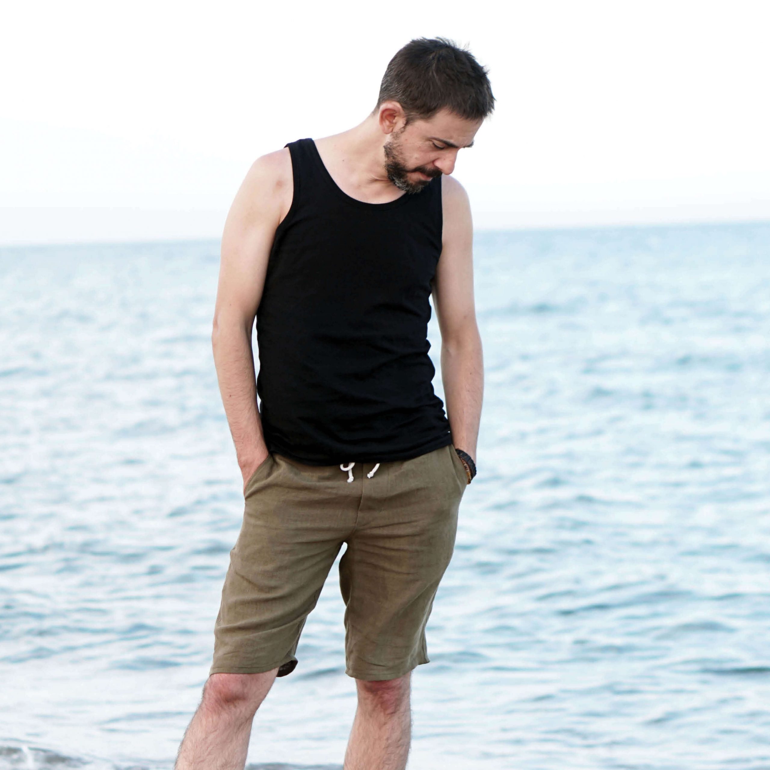 Man wearing the Men's Tank Top sewing pattern from Wardrobe by Me on The Fold Line. A vest top pattern made in jersey fabric with lycra or stretchy rib fabrics, featuring a straight fitted body, longer length, neckline and armscye binding.