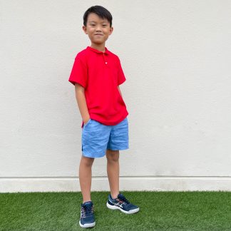 Child wearing the Children's Polo Shirt sewing pattern from Wardrobe by Me on The Fold Line. A polo top pattern made in light to medium weight jersey fabrics, featuring a two button placket, classic polo collar, front pocket, relaxed fit, side vents and short sleeves.