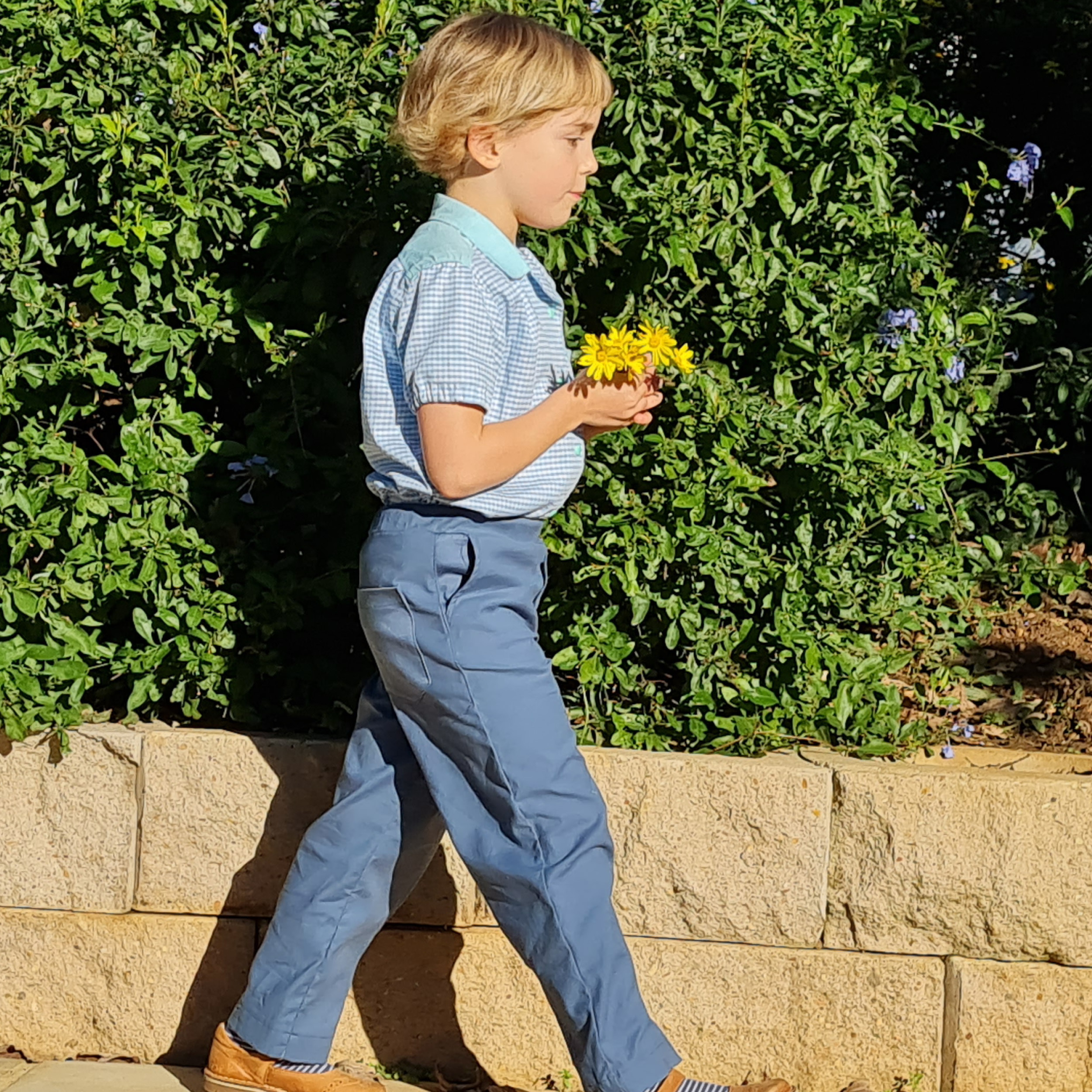 Child wearing the Children's Woven Pants sewing pattern from Wardrobe by Me on The Fold Line. A pull-on trouser pattern made in cotton, light canvas, denim or linen fabrics, featuring an elastic waist, straight leg, side and back pockets and decorative front fly.