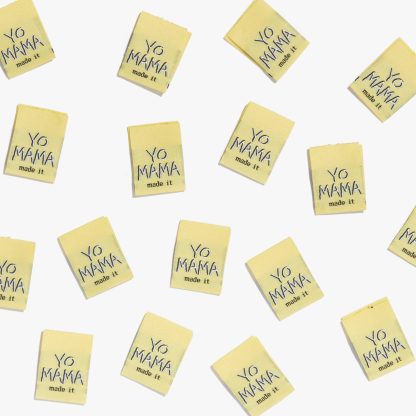 Photo showing 'Yo Mama Made It' Woven Labels from Kylie & The Machine on The Fold Line. A washable, durable and non-scratchy fabric label featuring a yellow background with white text, they are all ready to be sewn into your handmade clothes.