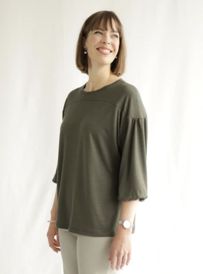 Woman wearing the Lorna Knit Top sewing pattern from Style Arc on The Fold Line. A knit top pattern made in jersey or cotton knit fabrics, featuring a hip-length, crew neck, front and back yokes, dropped shoulder, 3/4-length raglan sleeves with slight gathers at the sleeve head and elastic at the sleeve opening.