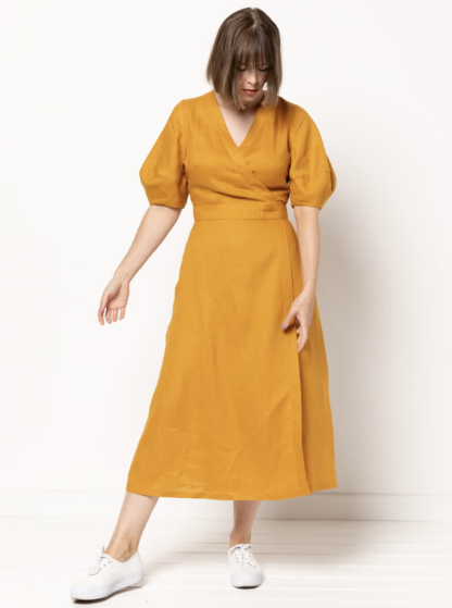 Woman wearing the Millicent Wrap Dress sewing pattern from Style Arc on The Fold Line. A wrap dress pattern made in linen, silk, crepe or rayon fabrics, featuring a wrap bodice and skirt with tie closure, neck and waist bands, bust darts, tuck details on the back bodice, elbow length lantern sleeves and side pockets.