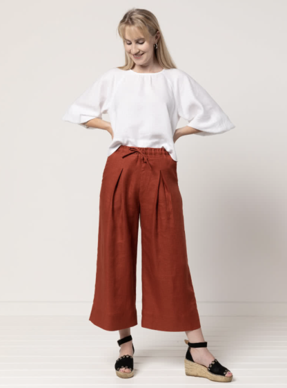 Woman wearing the Milan Woven Pant sewing pattern from Style Arc on The Fold Line. A trouser pattern made in linen or cotton fabrics, featuring a wide-leg, ankle-length, elastic waist with drawstring tie, inverted front pleats, back darts and side seam pockets.