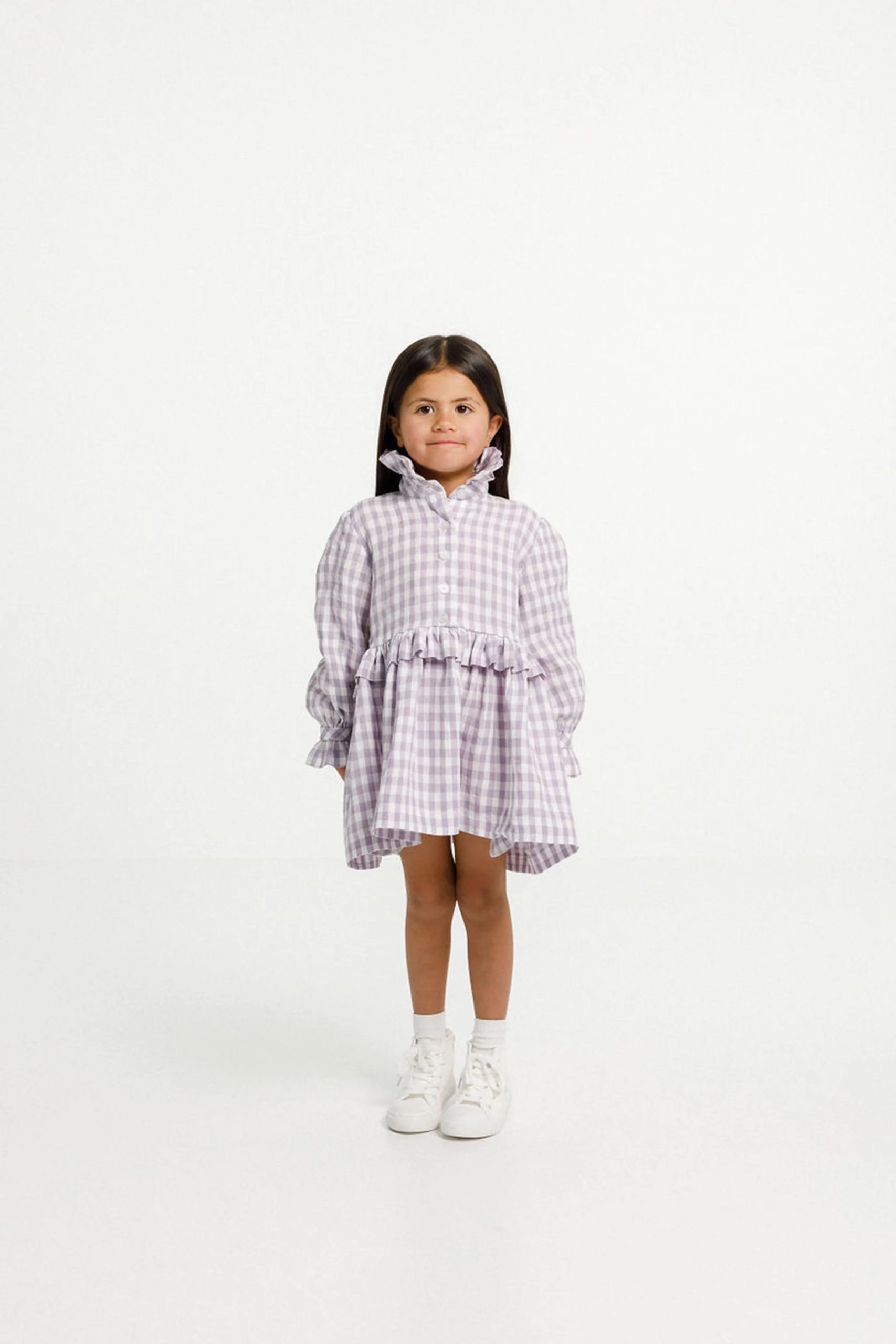 Child wearing the Ashling Dress sewing pattern from Papercut Patterns on The Fold Line. A dress pattern made in cotton, linen, silk, rayon or blends fabrics, featuring just above knee length, long sleeve with gathered cuffs, ruffle collar and waist, button up front and pockets.