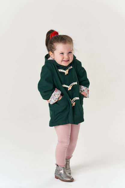 Child wearing the Baby/Child Walnut Duffle Coat sewing pattern from Poppy & Jazz on The Fold Line. A coat pattern made in melton, boiled wool, waxed canvas or waterproof fabrics, featuring a lined hood, patch pockets and three toggle front closure.