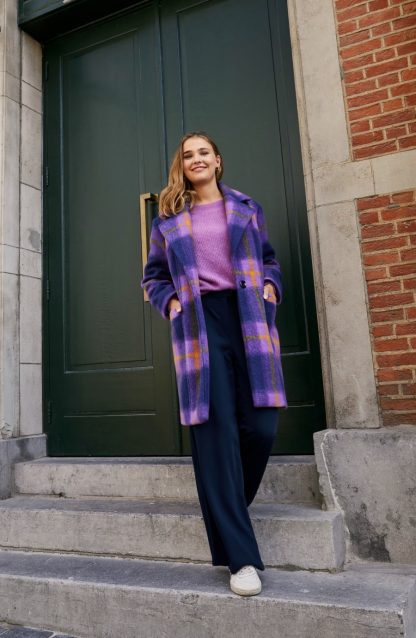 Woman wearing the Alex Coat sewing pattern from Atelier Jupe on The Fold Line. A Coat pattern made in wool, wool-blend, polyester, jacquard or heavy corduroy fabrics, featuring a mid-length, large collar and lapels, front pockets, back vent and single front button closure.