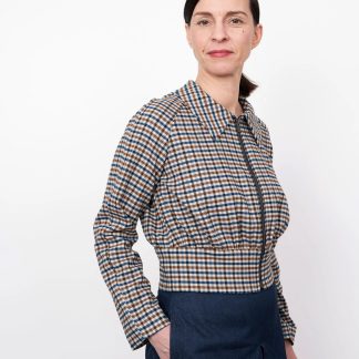Woman wearing the Cropped Jacket sewing pattern from The Assembly Line on The Fold Line. A jacket pattern made in mid-weight fabrics, featuring a short length, raglan sleeves, wide waistband, front zipper opening, full length sleeves and pointed collar.