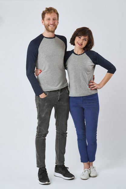 Man and Woman wearing the Men's and Women's Hebden T-shirt sewing pattern from Sew Over It on The Fold Line. A Tee pattern made in light to medium weight knit fabrics, featuring raglan sleeves, round neckline with neckband, full-length or three-quarter sleeve options, contrasting fabrics with the sleeves and neckband in one colour.
