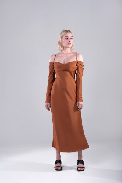 Woman wearing the Leoncia Dress sewing pattern from Vikisews on The Fold Line. A dress pattern made in satin, viscose, stretch crepe or silk fabrics, featuring a close fit, bias cut, centre back seam, adjustable spaghetti straps, draped front bodice, bias-cut sleeves are long, narrow, and draped at the top and midi length.