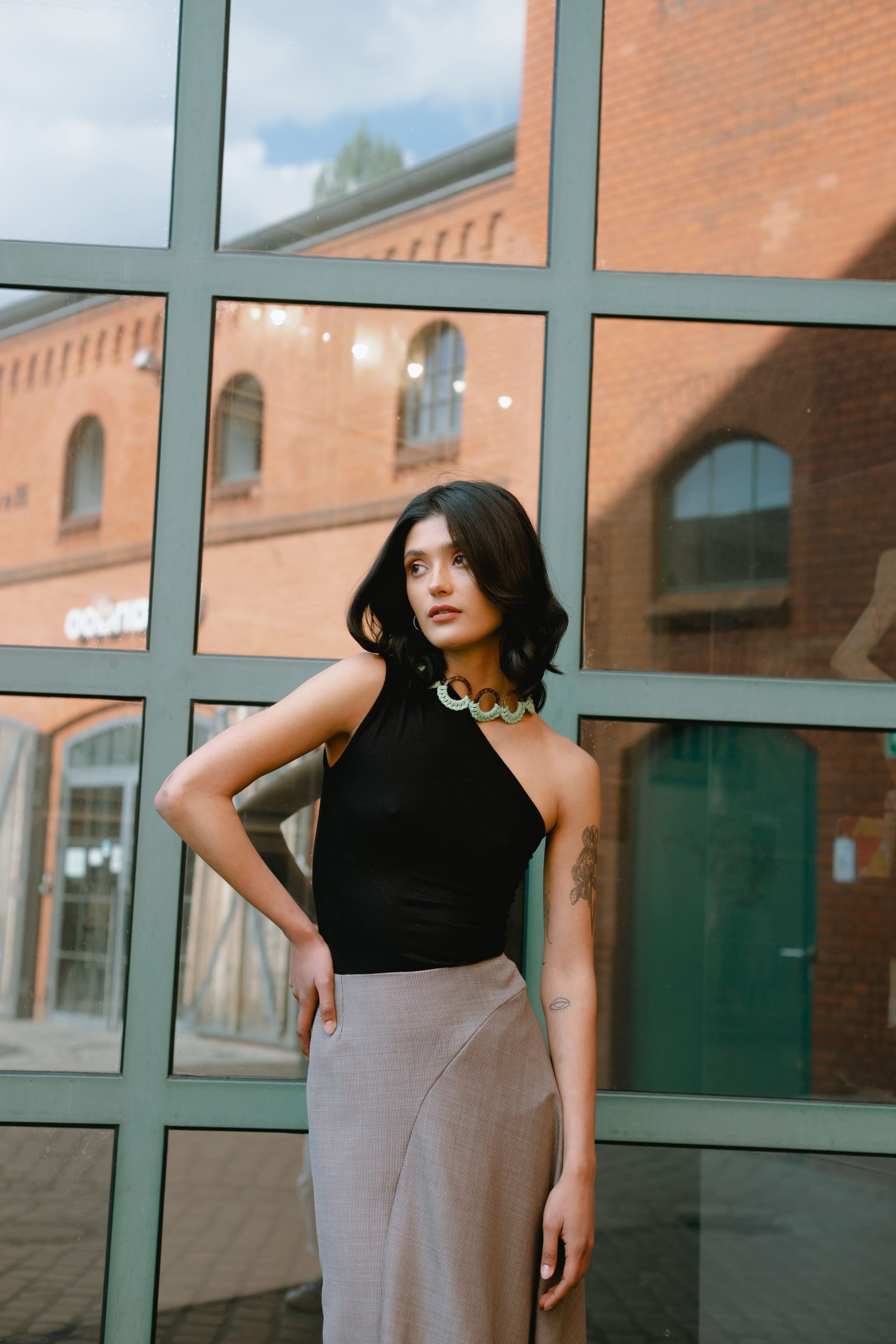 Woman wearing the Cara Top sewing pattern from JULIANA MARTEJEVS on The Fold Line. A knit top pattern made in cotton jersey fabrics, featuring an asymmetric style with cold shoulder, close fitting and sleeveless.