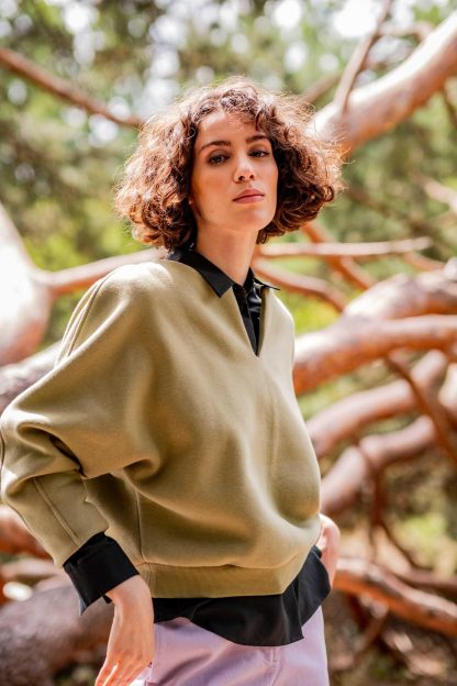 Woman wearing the Elaine Sweater sewing pattern from Fibre Mood on The Fold Line. A sweater pattern made in knit fabrics, featuring balloon shaped sleeves, contoured darts in the sleeve hem, V keyhole neckline and relaxed ribbed trim hem band.