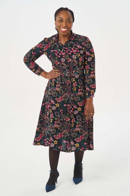 Woman wearing the It Nicole Dress sewing pattern from Sew Over It on The Fold Line. A shirt dress pattern made in cotton poplin, cotton lawn, crepe, viscose or tencel fabrics, featuring a buttoned front, collar and collar stand, midi A-line skirt with gently curved hem, bust and waist darts, pockets, long sleeves with shirt cuffs and midi length hem.