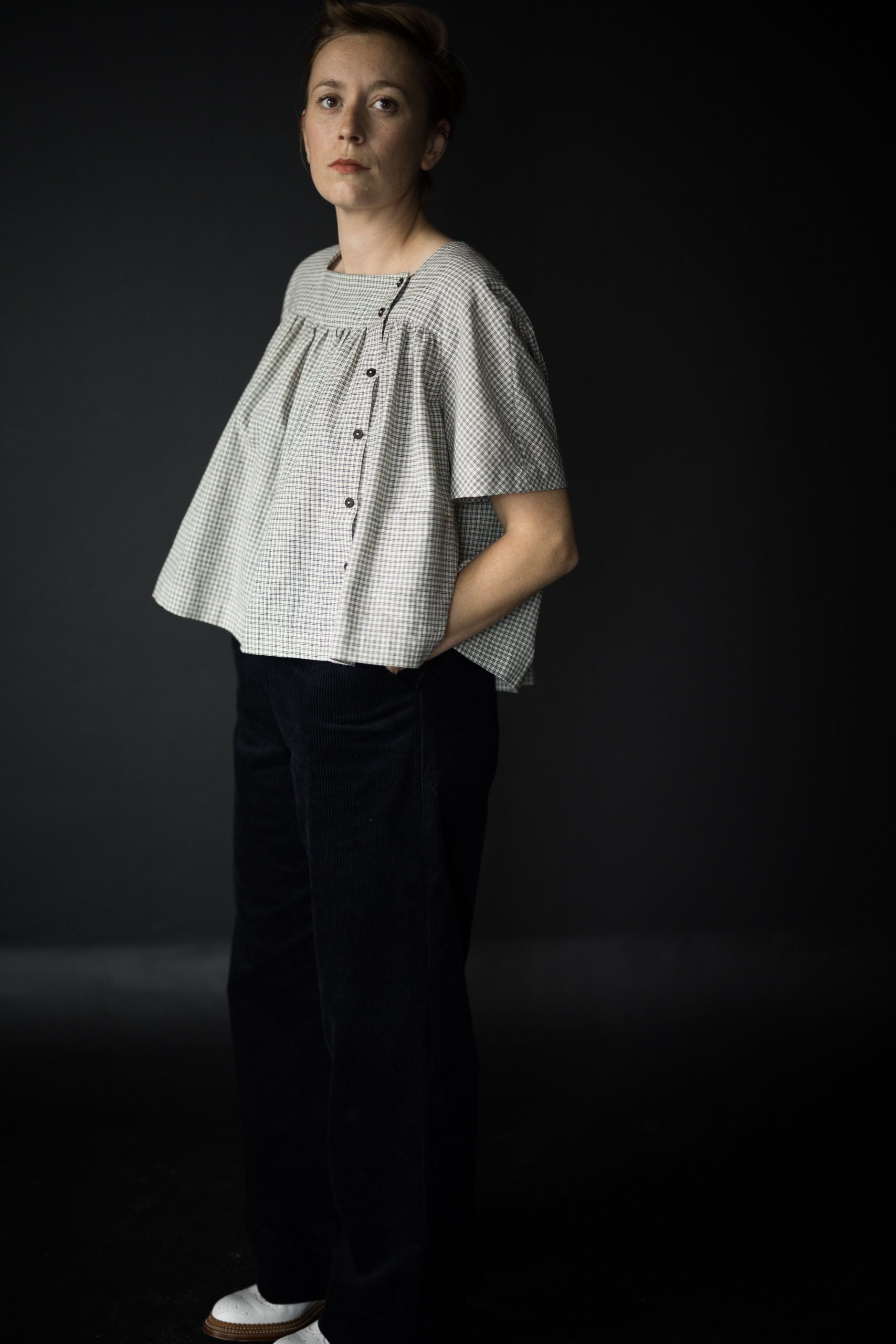 Woman wearing the The Omilie Top sewing pattern from Merchant & Mills on The Fold Line. A top pattern made in linen, brushed cotton, cotton lawn, cotton poplin, tencel, Indian handlooms, linen or cotton double gauze fabrics, featuring a smock style, patch pockets, square neck, short sleeves and off centre front button closure.
