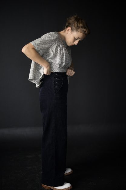 Woman wearing The Quinn Trousers sewing pattern from Merchant & Mills on The Fold Line. A trouser pattern made in cotton twill, denim, corduroy, light to medium weight woollens or linen fabrics, featuring full length wide legs, back welt pockets and front pockets with button openings.