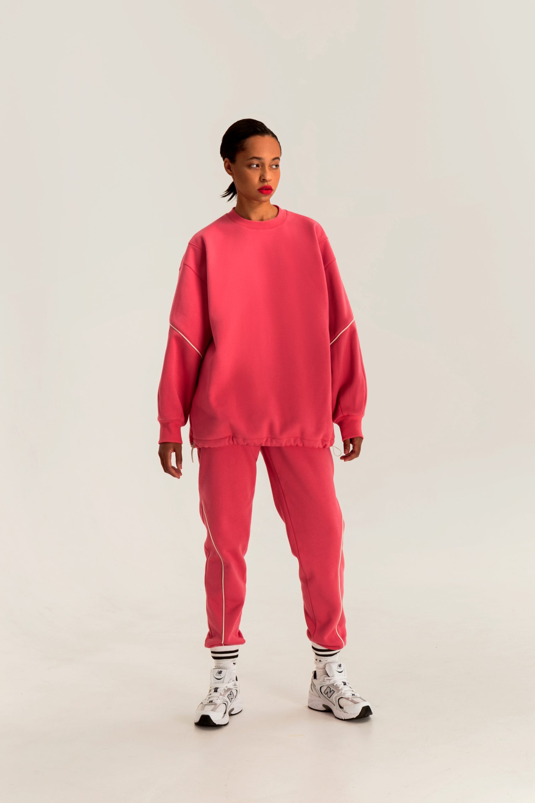 Woman wearing the Roxy Sweatshirt sewing pattern from Vikisews on The Fold Line. A sweatshirt pattern made in heavyweight sweatshirt fleece fabrics, featuring an oversized straight silhouette, shoulder darts, round neckline with ribbed neckband, full-length sleeves with ribbed cuffs, below-hip length, the hem has an elastic cord and toggle stoppers.