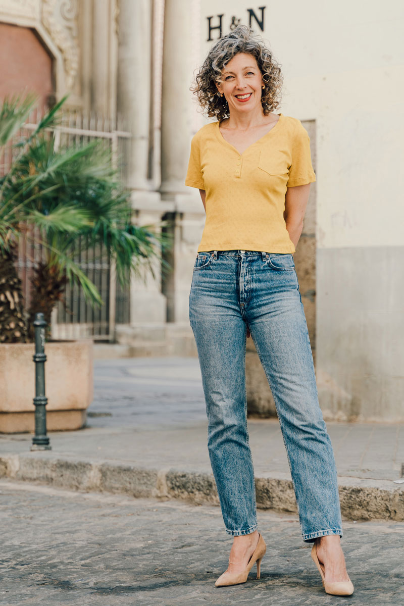 Woman wearing the Strasbourg Henley Top sewing pattern from Liesl + Co on The Fold Line. A top pattern made in jersey fabrics, featuring a close-fit, pullover V-neck, three button front placket, cropped length, small chest pocket and short sleeves.