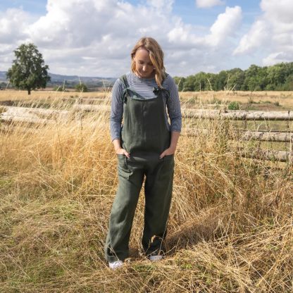 Woman wearing the Ferdi Dungarees sewing pattern from Sew Me Something on The Fold Line. A dungarees pattern made in medium to light weight cotton, light weight denim, linen, corduroy, double gauze or medium to heavy weight viscose fabrics, featuring a relaxed fit, wide-leg, deep patch pockets, and shoulder tie fastenings.