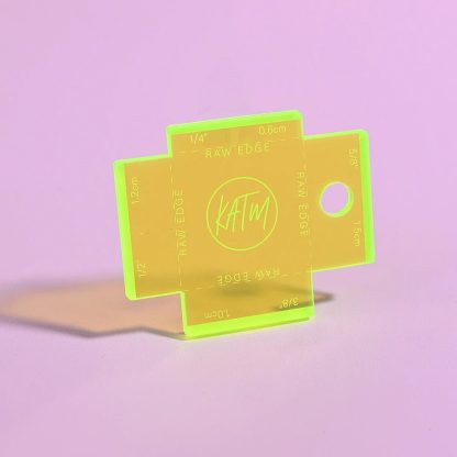 Photo showing the Label Gauge from Kylie & The Machine on The Fold Line. This fluorescent yellow acrylic gauge with laser etched measurements will help you to position your label perfectly, it includes the four most common seam allowances.