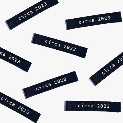 Photo showing 'Circa 2023' Cotton Labels from Kylie & The Machine on The Fold Line. A washable, durable, and non-scratchy cotton label featuring black coloured backgrounds with white text, they are all ready to be sewn into your handmade clothes.
