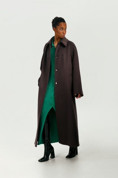 Woman wearing the Hayden Coat sewing pattern from Vikisews on The Fold Line. A coat pattern made in coating-weight cashmere or wool, and heavyweight tweed fabrics, featuring a semi-fit, trapeze shape, raglan sleeves flared at the hem, bust darts, front welt pockets, turn-down collar with collar stand, midi length, fully lined and snap fasteners.